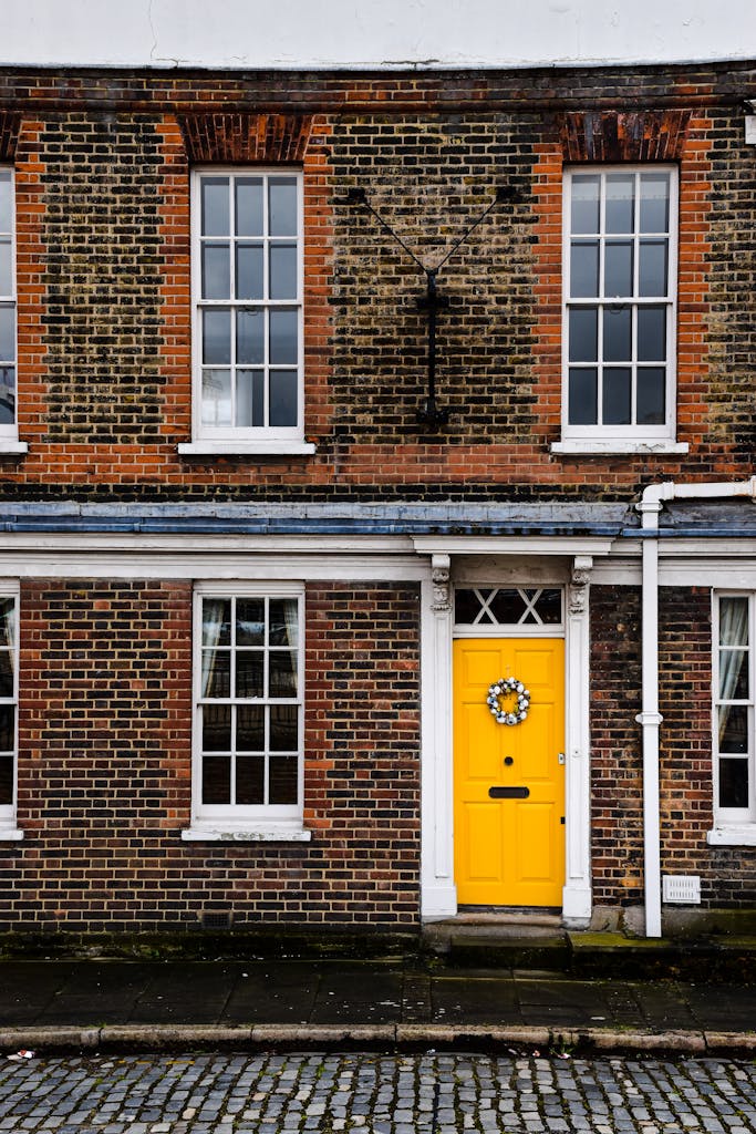 Classic English townhouse facade with a bright yellow door, exuding vintage charm.