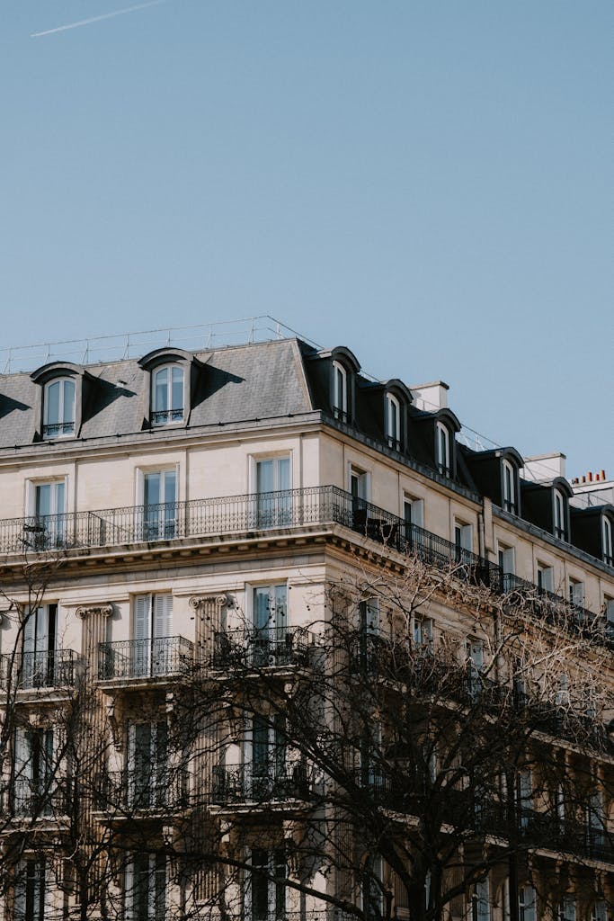 A classic Parisian-style apartment building against a clear blue sky, showcasing urban architecture.