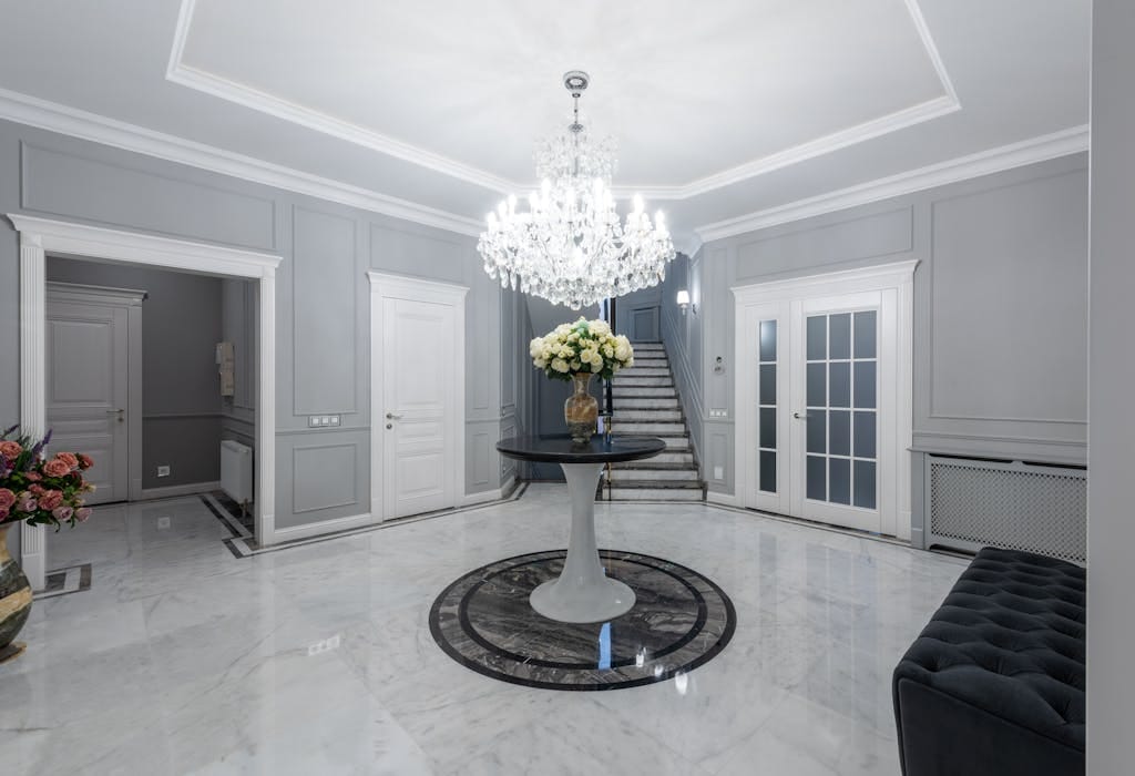 Interior of modern hall with glowing chandelier and soft sofa on sparkling clean floor