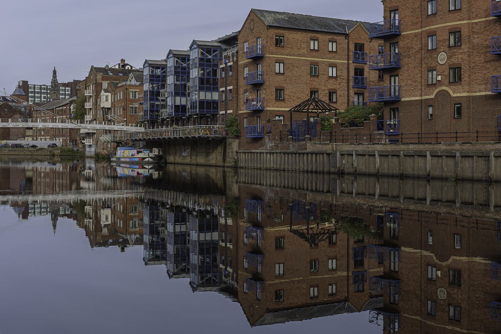 Scenic view of Leeds canal with historic buildings reflecting on tranquil water.