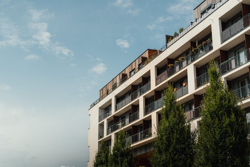 Stylish modern apartment building under a clear blue sky, showcasing balconies and urban architecture.