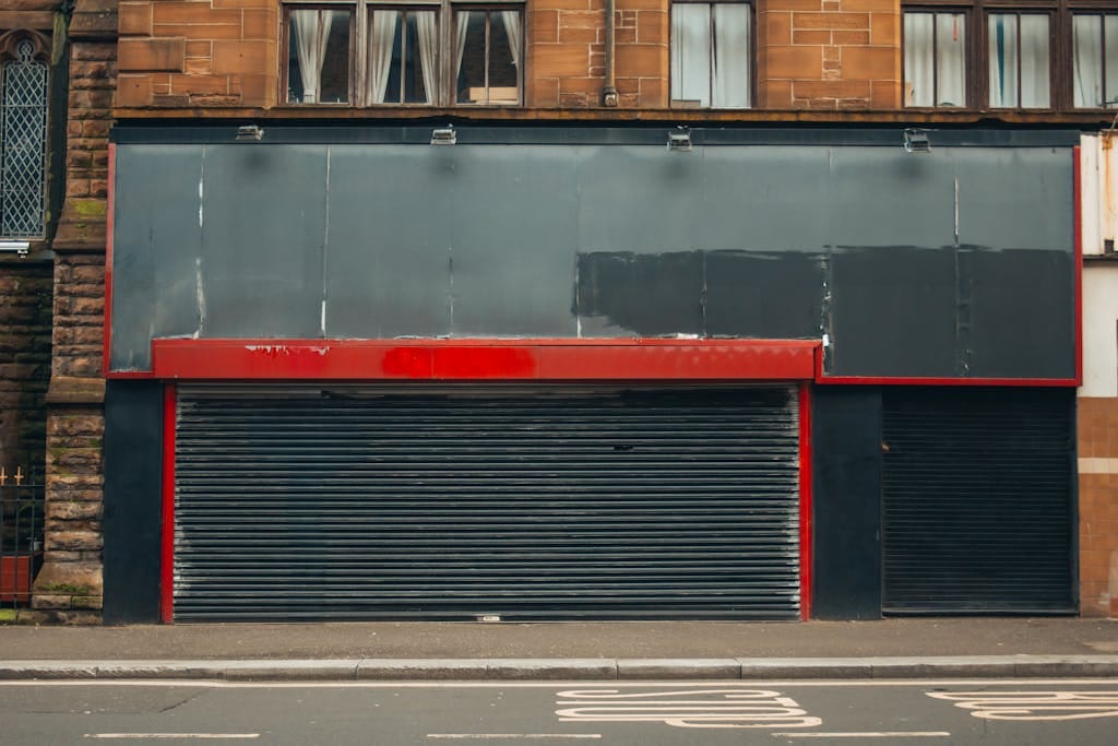 Urban storefront with closed shutters and vibrant red and black facade; perfect for city street scenes.
